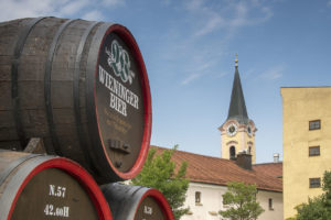 Das riesige Wieninger Bierfass vor der Brauerei mit der Kirche St. Andreas im Hintergrund © ROHA Fotothek Teisendorf